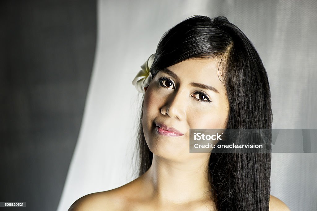 Beautiful Asian Woman Beautiful Asian woman with a frangipani flower in her hair. This image was made with a Nikon D800 full frame camera and Nikon 105mm prime lens. 30-39 Years Stock Photo