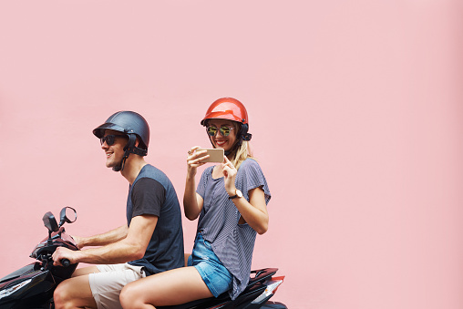 Shot of a carefree young couple taking a photograph while riding on a scooter against a pink backgroundhttp://195.154.178.81/DATA/i_collage/pu/shoots/806308.jpg
