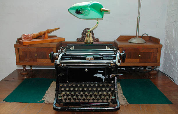 Antique Typewriter An antique manual typewriter on a antique wooden desk. gold desk lamp stock pictures, royalty-free photos & images
