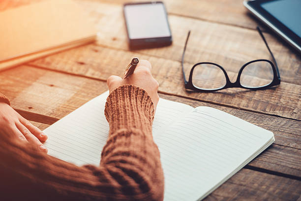 Planning new day. Close-up image of woman writing in notebook with copy space while sitting at the rough wooden table Creative Writing stock pictures, royalty-free photos & images