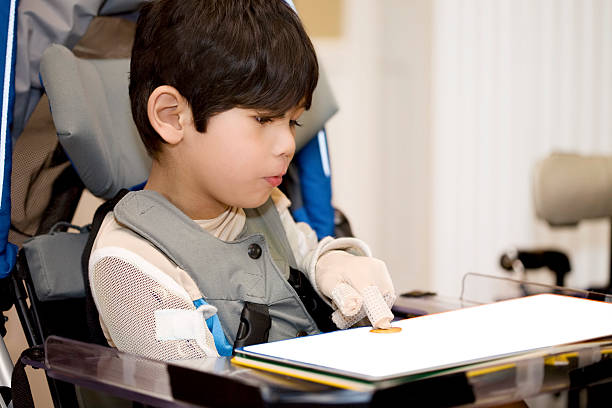 Five year old disabled boy studying in wheelchair stock photo