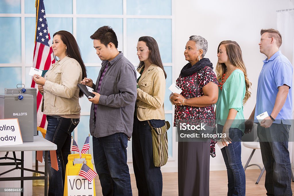 American voters stand in line to cast ballots. November elections. Multi-ethnic, mixed age group of people stand in line to cast their ballot in the November USA elections at a local polling station.  Voting Stock Photo