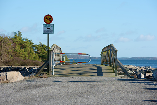 Karlshamn, Sweden - February 04, 2016: Signs telling that it is forbidden to drive mopeds and let dogs loose on the other side of the gate to protect the wildlife. A bridge takes you to the island.