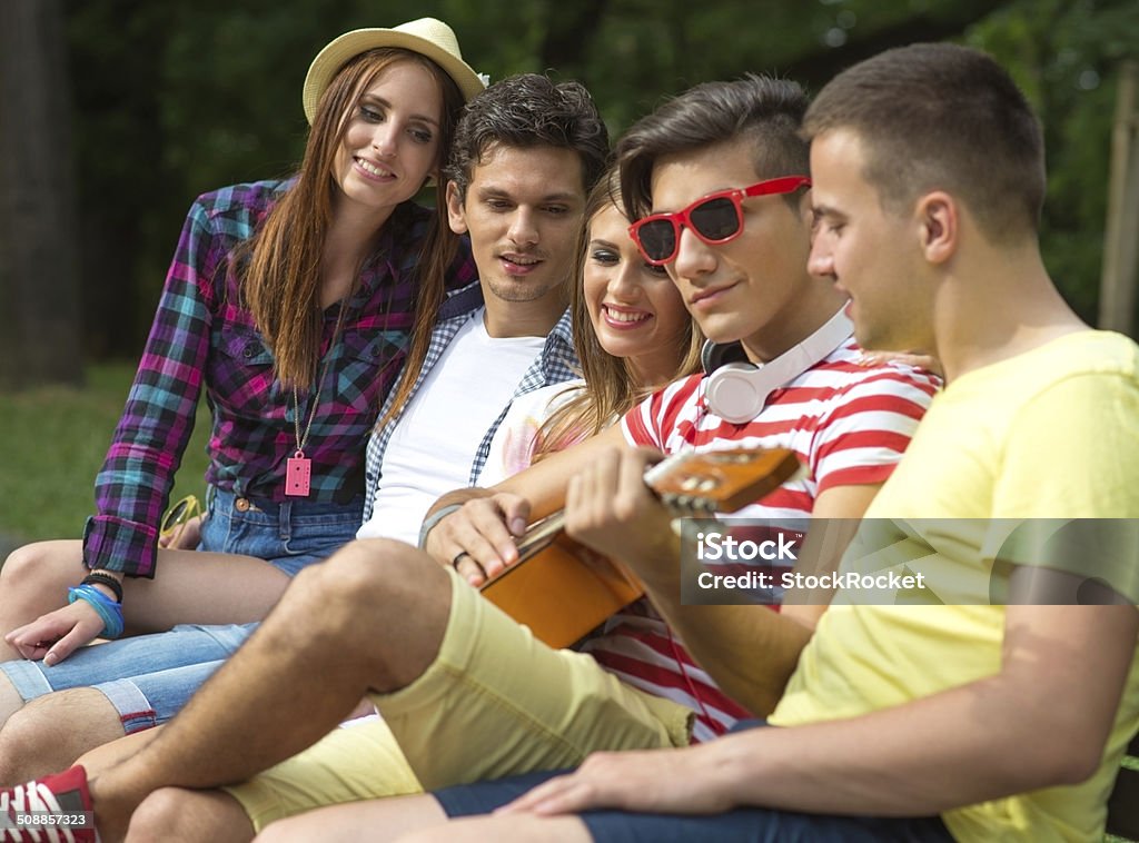 Group of  friends playing music Group of young people enjoying in the park. 20-24 Years Stock Photo