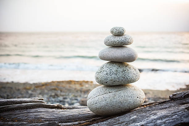 Inukshuk Cairn on driftwood on beach Inukshuk cairn sitting on driftwood on beach at sunset cairns photos stock pictures, royalty-free photos & images