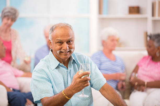 。乾杯！ ハッピー、インドの民族老人男性ドリンク白ワインをお届けします。 ご友人とご賞味ください。 - real people blue white friendship ストックフォトと画像