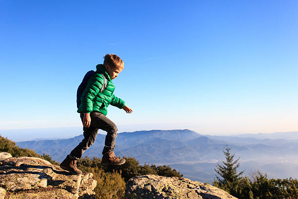 little boy with backpack hiking in scenic mountains