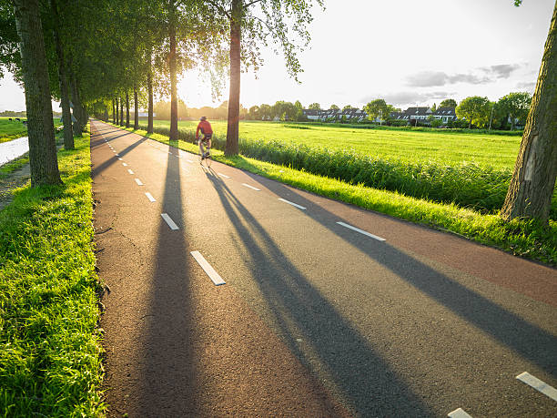 ciclista andar no país estrada ao pôr do sol - netherlands place imagens e fotografias de stock