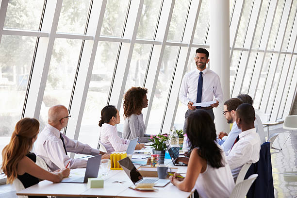 Hispanic Businessman Leading Meeting At Boardroom Table