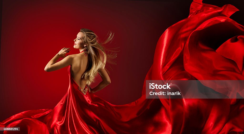 Woman Red Dress Dancing, Fashion Model Flying Cloth Fabric Woman in Red Dress Dancing, Fashion Model with Flying Cloth Fabric over red background Dress Stock Photo