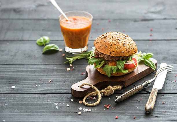 Fresh homemade burger on dark serving board with spicy tomato