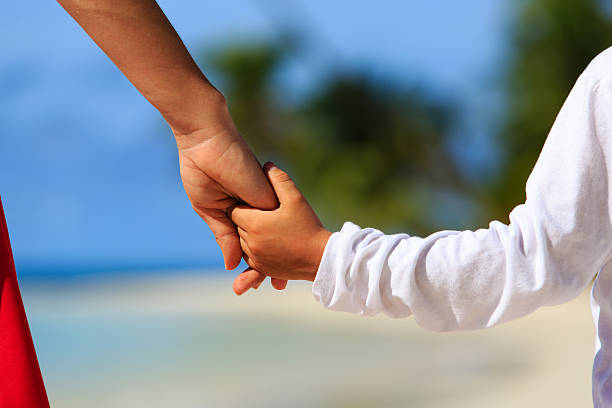 istock mother and son holding hands on beach 508883390