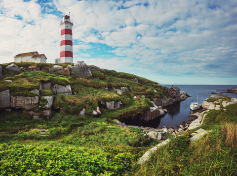 A fishing boat is moored in a narrow harbour at Sambro Island Lighthouse.  Built in 1758 it is the oldest operating lighthouse in North America.