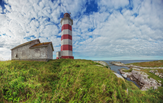 A fishing boat is moored in a narrow harbour at Sambro Island Lighthouse.  Built in 1758 it is the oldest operating lighthouse in North America.