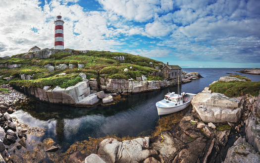 A fishing boat is moored in a narrow harbour at Sambro Island Lighthouse.  Built in 1758 it is the oldest operating lighthouse in North America.