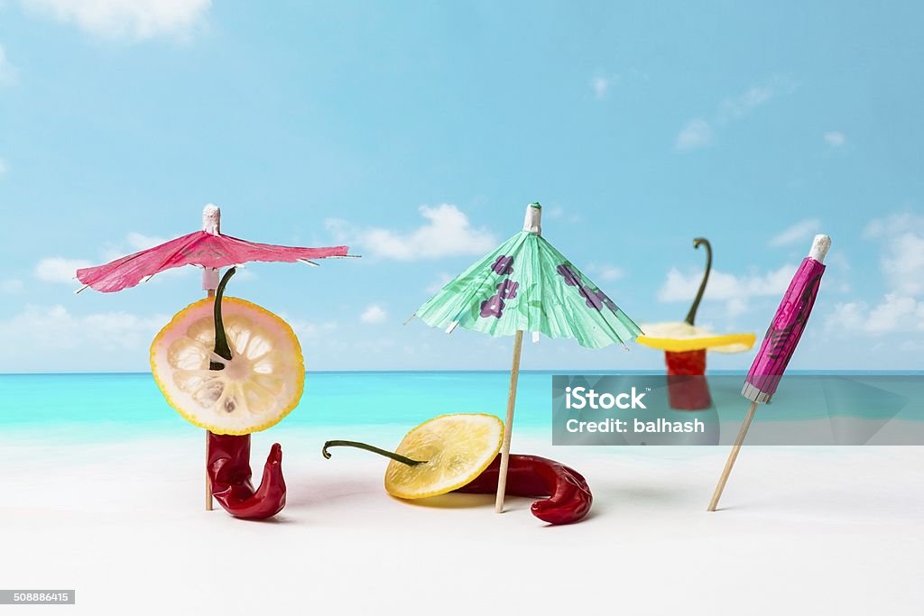 Acapulco Still life of three red hot chili peppers on a sunny beach under the umbrellas and waistdeep in the water. All three amigos are wearing sombreros even while swimming. The time to have a rest Arts Culture and Entertainment Stock Photo