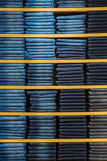 Neat stacks of folded jeans on the shop shelves stock photo