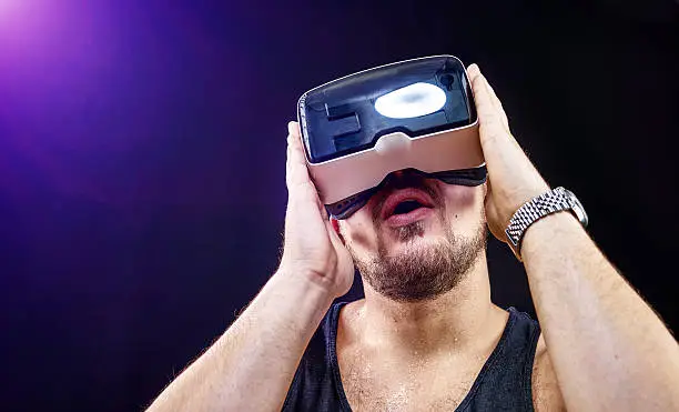 Man has fun using his Virtual Reality VR glasses head mounted display