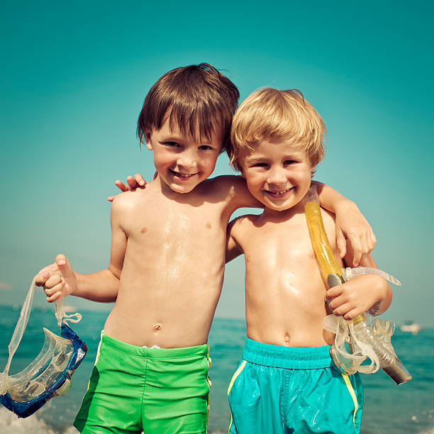 Happy little boys with scuba masks by the sea