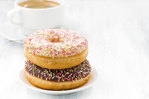 istock glazed donuts and cup of coffee on white table 508900482
