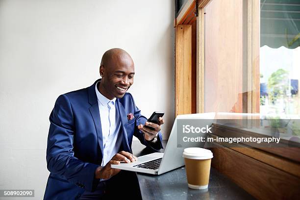 Felice Uomo Daffari Africani Con Telefono Al Café - Fotografie stock e altre immagini di In movimento - In movimento, Lavorare, Uomini