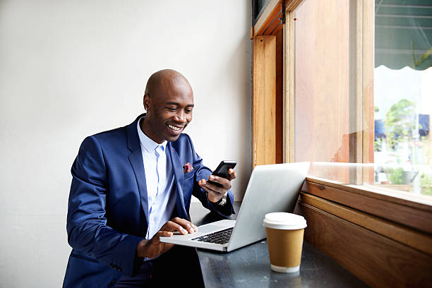 を使用して幸せなアフリカの実業家のカフェ電話 - business blue business person businessman ストックフォトと画像