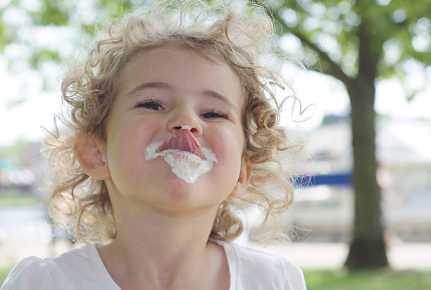 Little girl enjoying some chocolate cake. She is sucking the chocolate from her fingers.