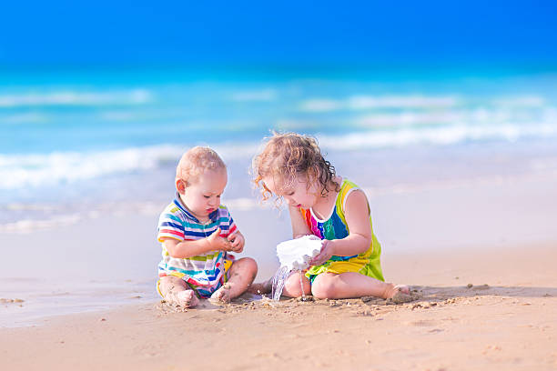 istock Little kids playing on the beach with huge sea shell 508906279