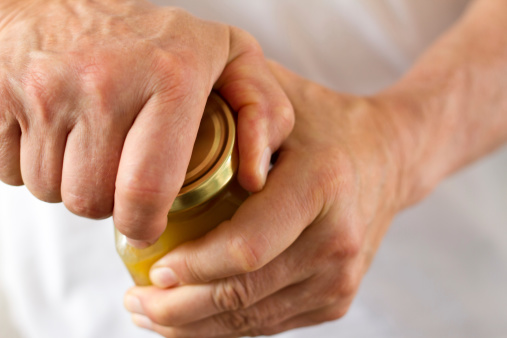 Close-up shot of strong male hands twisting open a stubborn jar lid.