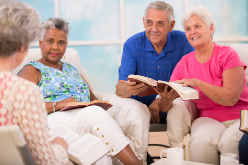 Selective focus on bibles. Group of senior adults during a bible study.  Multi-ethnic group reading bible together. 
