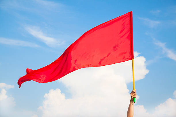 Hand waving a red flag with blue sky background stock photo