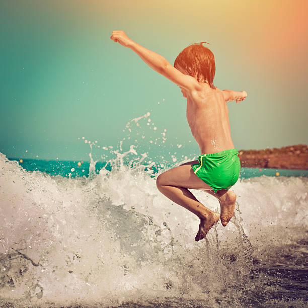 Happy little boy playing in waves