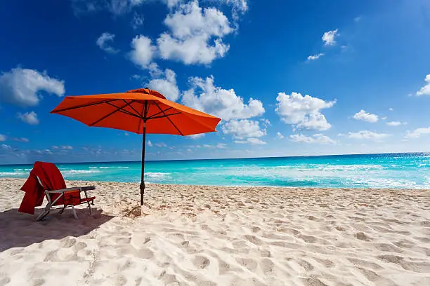 Beautiful orange umbrella and chair on the white sand beach