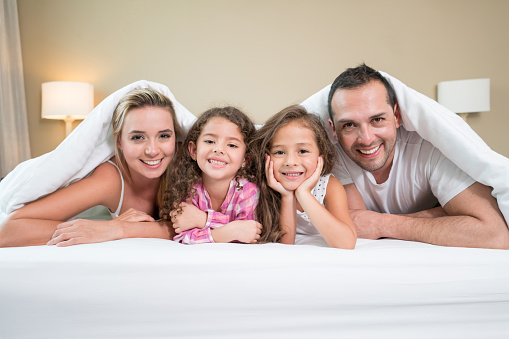 Portrait of a beautiful Latin American family in bed looking at the camera and smiling
