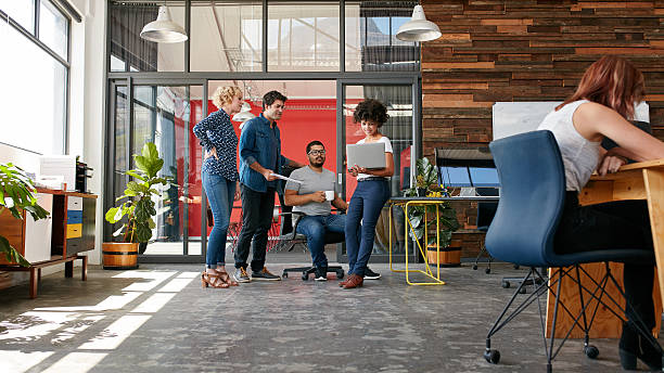 Group of creative people having a meeting Portrait of group of creative people having a meeting with a laptop in a modern office. Business people having relaxed conversation over new project. design studio stock pictures, royalty-free photos & images