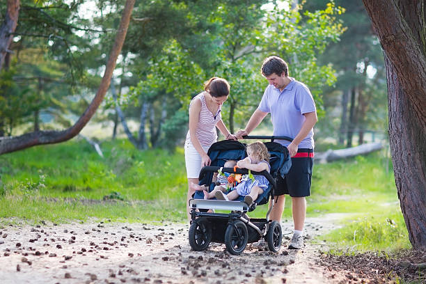 junge familie wandern und zwei kinder in einem kinderwagen - gehen sportdisziplin stock-fotos und bilder