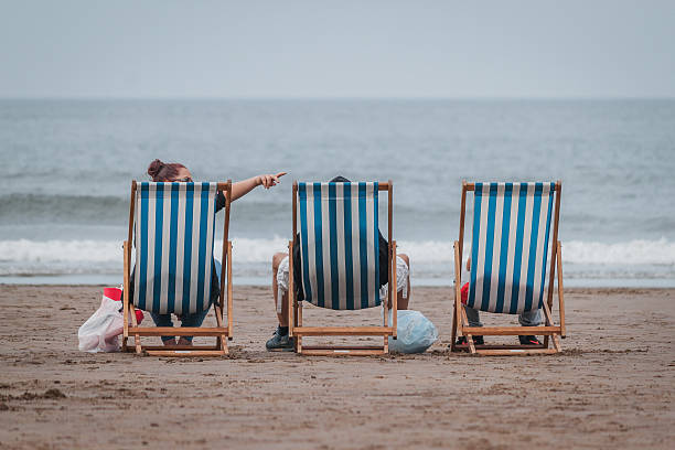 Blankenberge, West-Flanders Belgium  April 15, 2022: row of red lounge chairs waiting for tourists in front of terraced residential flats on the beach