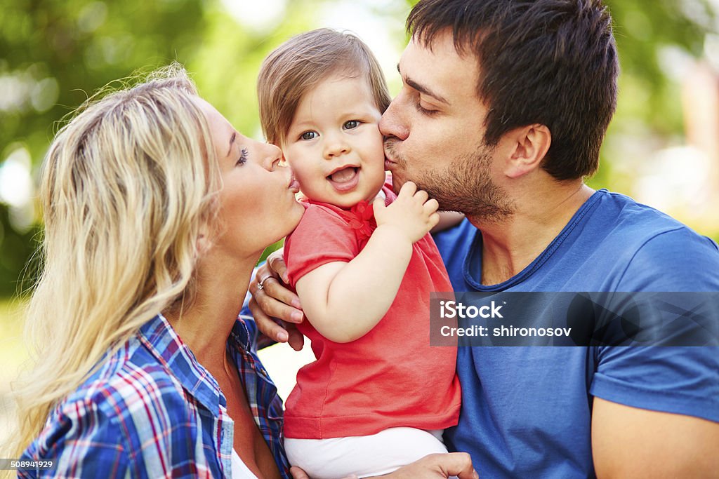 Expressing affection Careful parents kissing their small daughter Baby - Human Age Stock Photo