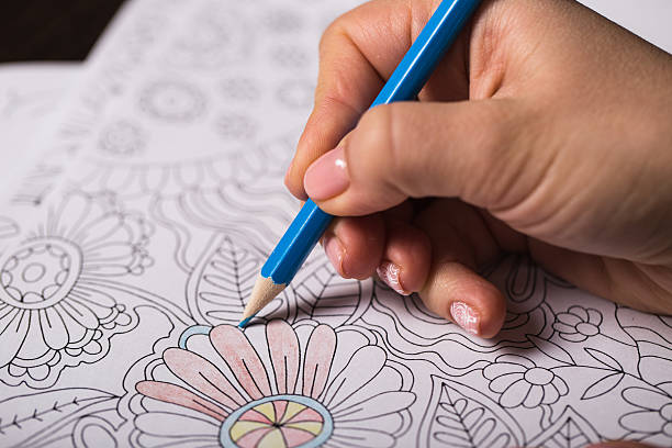 Girl paints a coloring book for adults with crayons Girl paints a coloring book for adults with crayons adult coloring pages mandala stock pictures, royalty-free photos & images