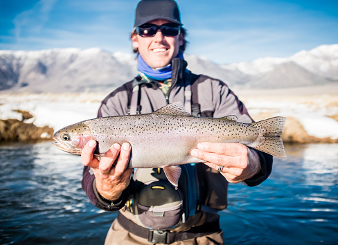 Proud Fisherman Holding Up His Rainbow Trout In Winter