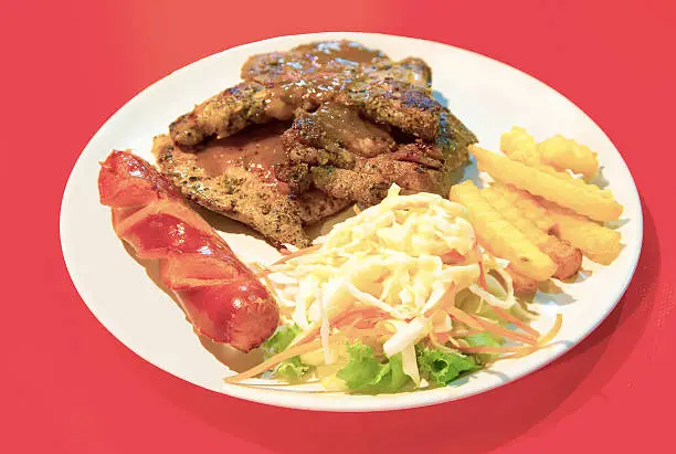 Grilled Porkchop Steak with salad, Smoked Sausage and French Fries.