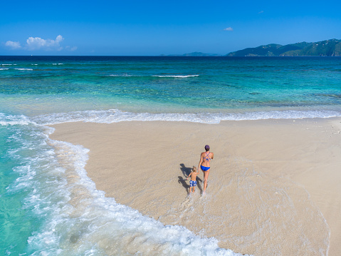 Mother and child walking on tropical beach in the British Virgin Islands