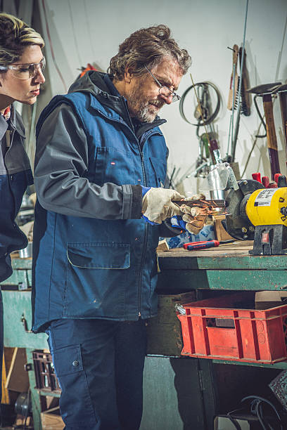istock Senior Man Teaching Young Woman Grinding Metal 508953094