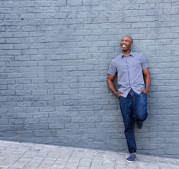 istock Smiling african guy leaning against gray wall 508953176