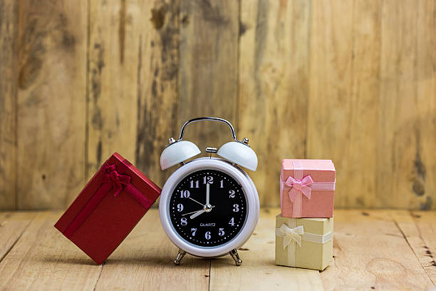 istock White classic alarm clock with gift box on wood background 508955196