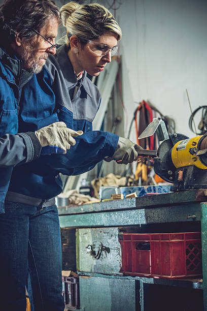 istock Man Teaching Woman How to Grinding Metal in Mechanical Workshop 508955436