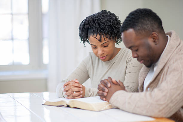 religious ethnic couple praying with a bible - christendom stockfoto's en -beelden