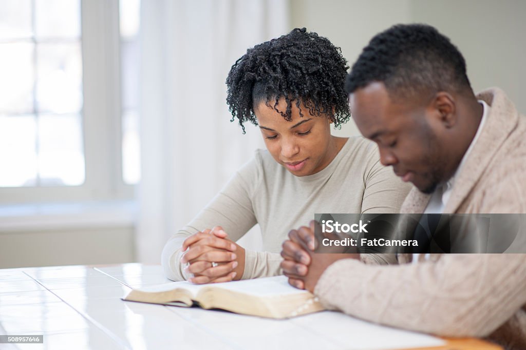 Religious Ethnic Couple Praying with a Bible Christian couple praying together. Praying Stock Photo