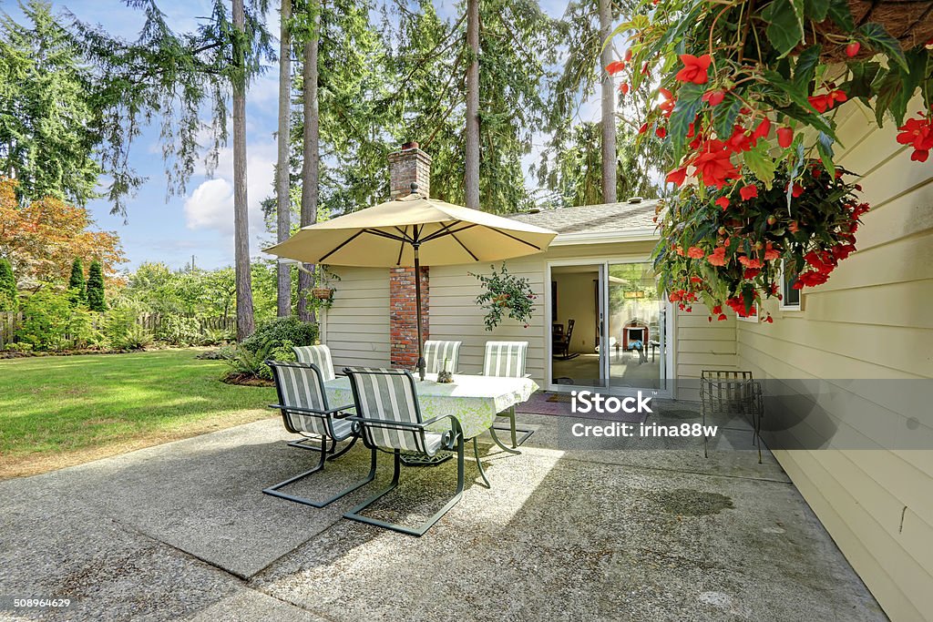 Countryside house backyard  with patio table Countryside house exterior with small patio area. View of patio table set with umbrella Architecture Stock Photo
