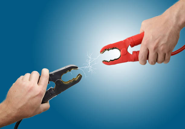 Power connection Hands holding jump start connectors with sparks between jumper cable stock pictures, royalty-free photos & images